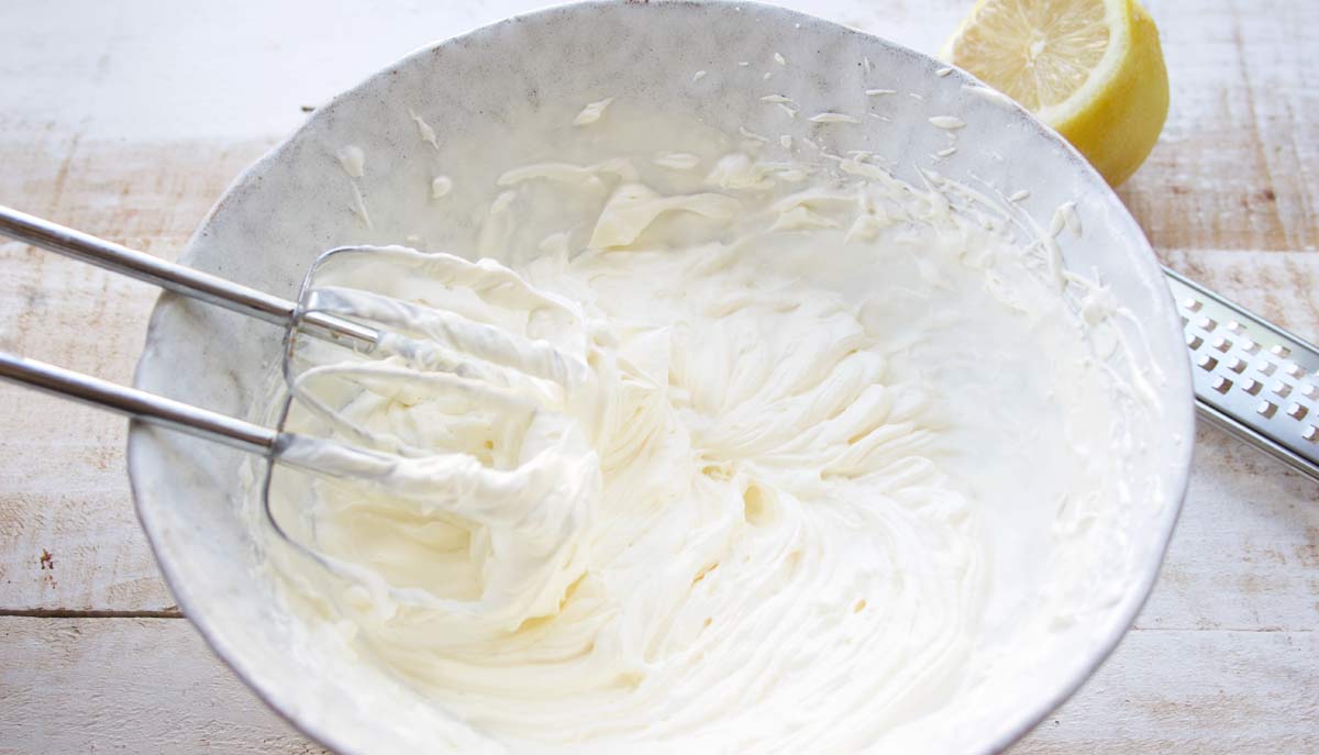 whipping cream in a bowl with a handheld electric mixer