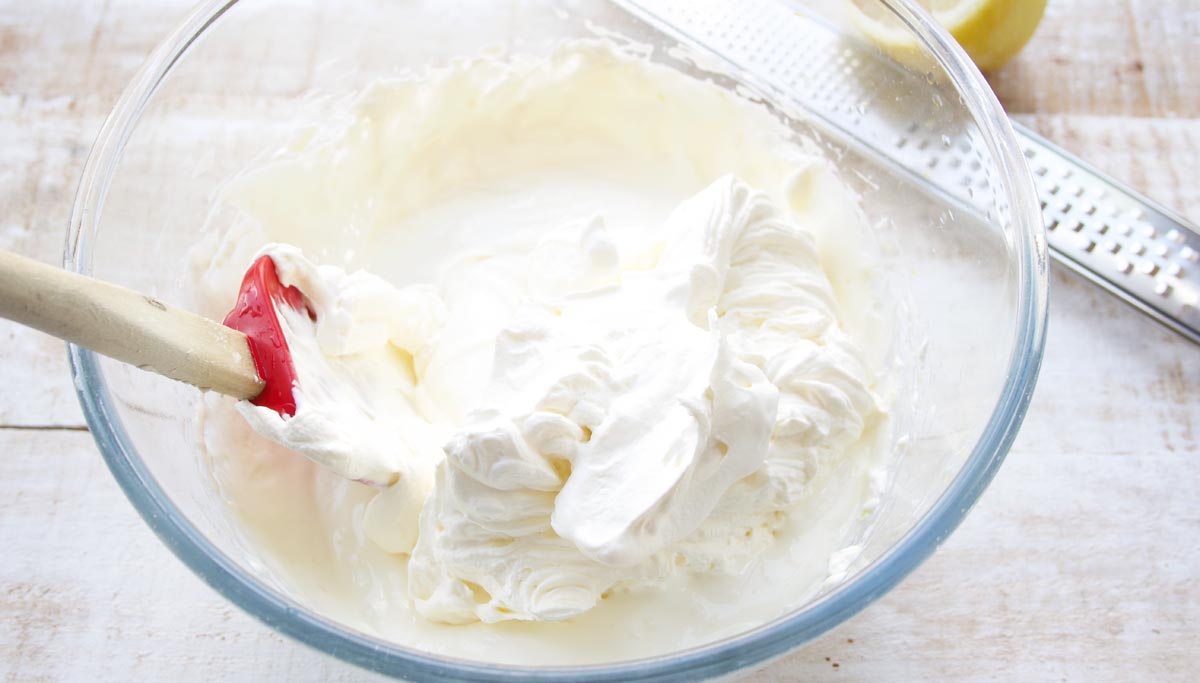whipped cream and cream cheese mix and a spatula in a bowl