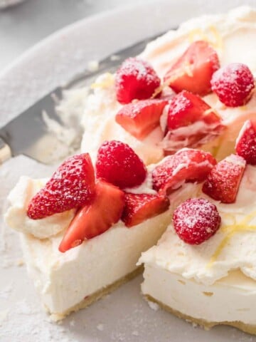 a no bake sugar free cheesecale topped with whipped cream, raspberries and strawberries