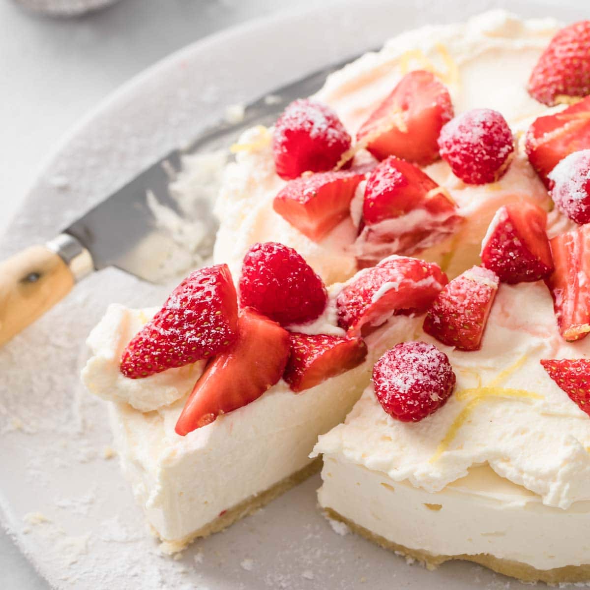 a no bake sugar free cheesecale topped with whipped cream, raspberries and strawberries