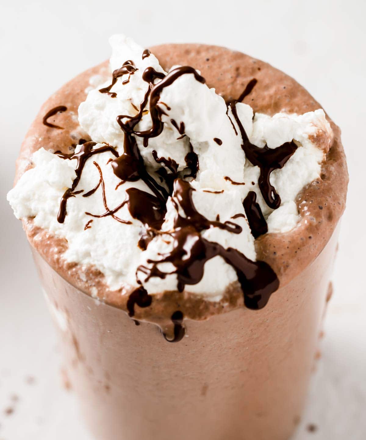 a chocolate flavoured keto milkshake topped with whipped cream and melted chocolate