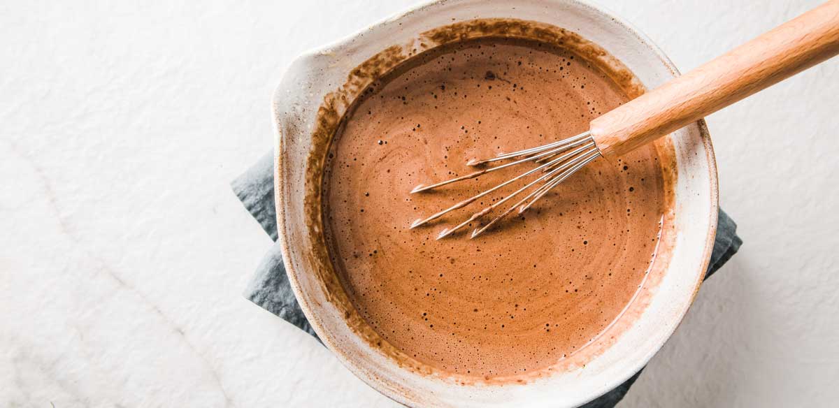 cream, cocoa powder, egg yolks and allulose mixed together in a bowl