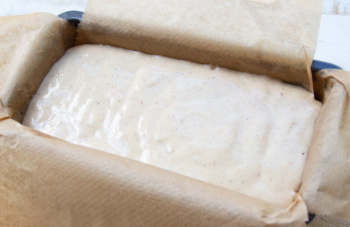batter in a loaf pan lined with parchment paper 
