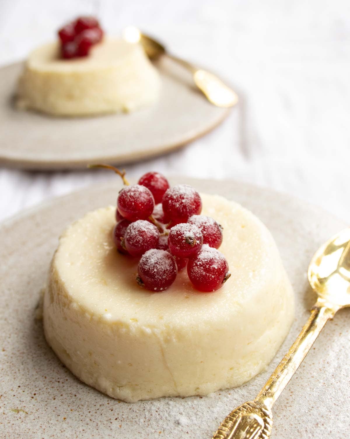 a single serve cheesecake inverted onto a plate and topped with redcurrants