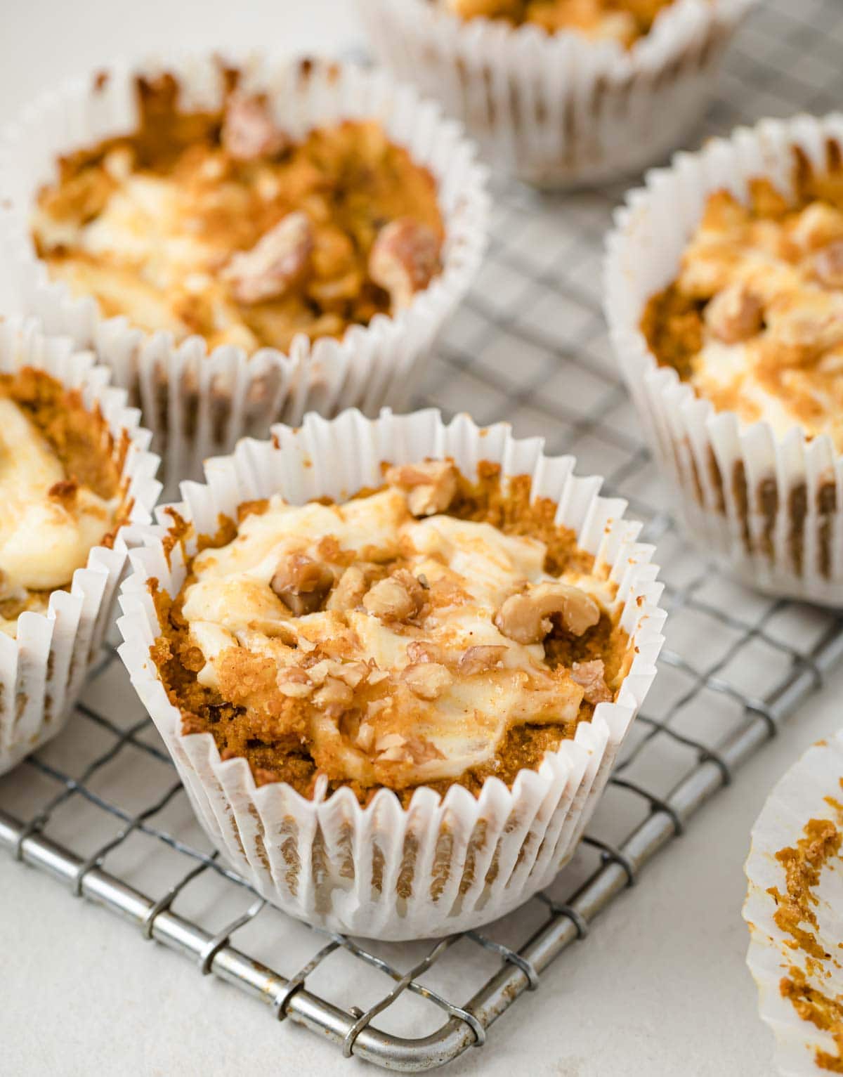 pumpkin cheesecake muffins in paper cases on a cooling rack