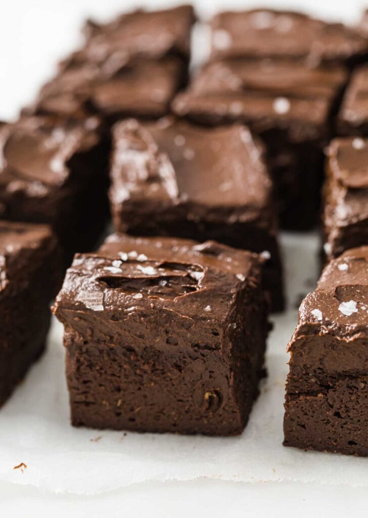 brownie squares topped with chocolate frosting and sea salt flakes