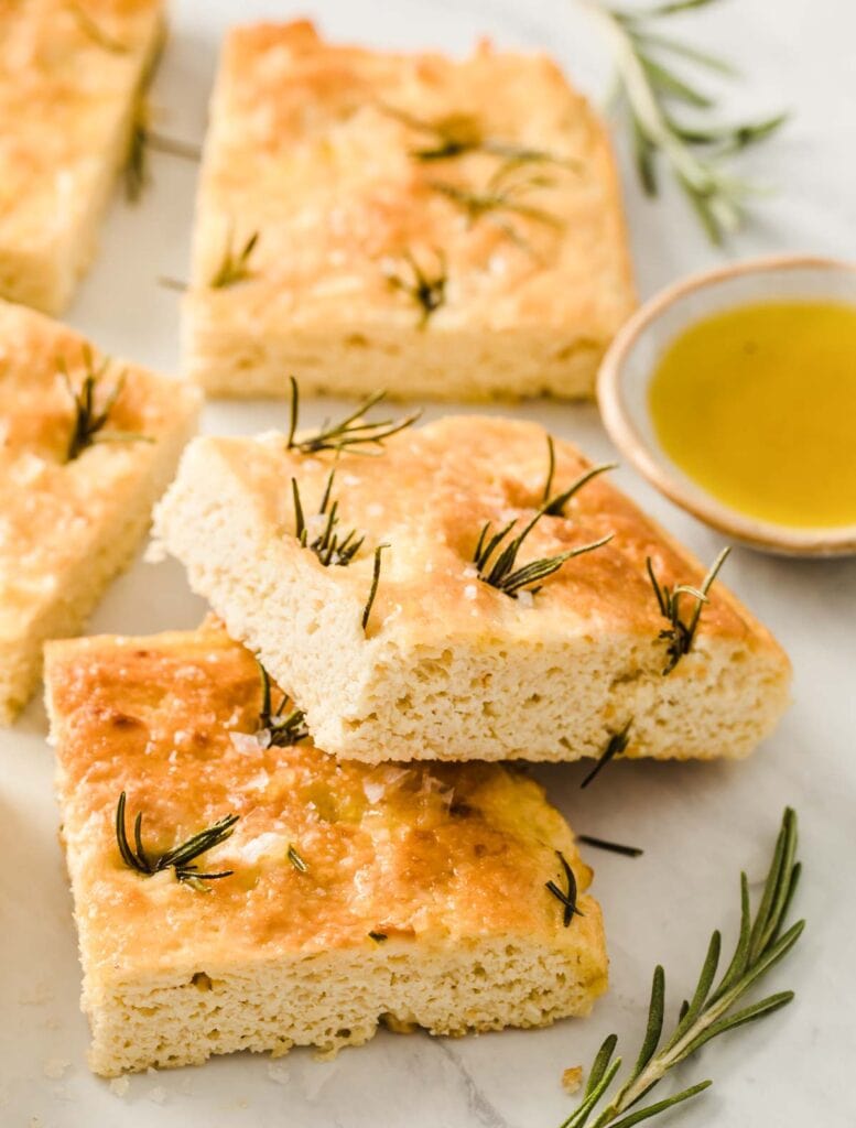 squares of focaccia bread with rosemary sprigs and a small dish of olive oil