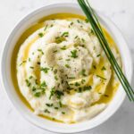 cauliflower mash in a bowl with chopped chives and melted butter