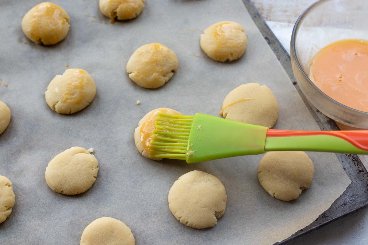 brushing egg wash onto cookies with a brush
