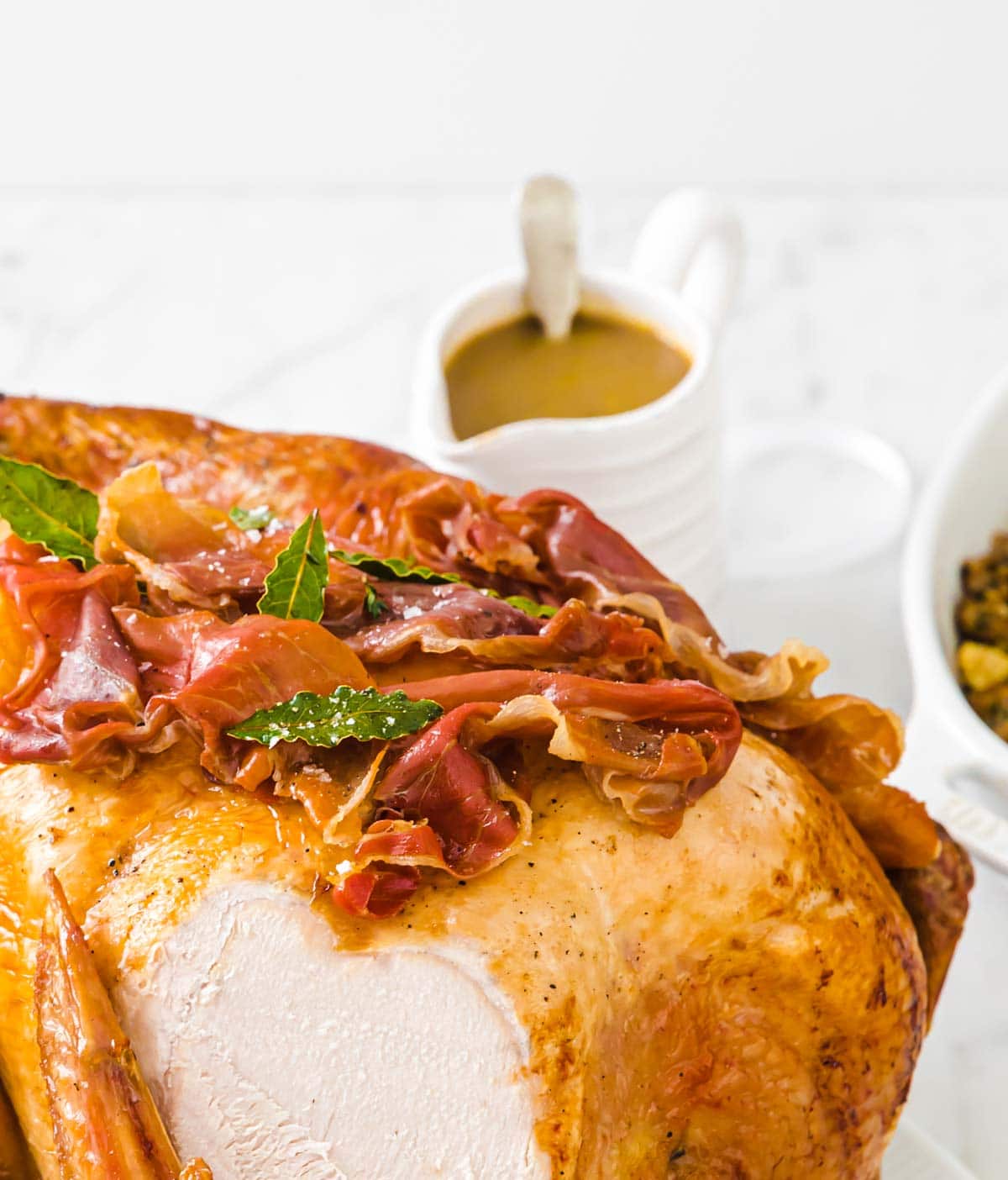 a jug of gravy behind a roasted turkey
