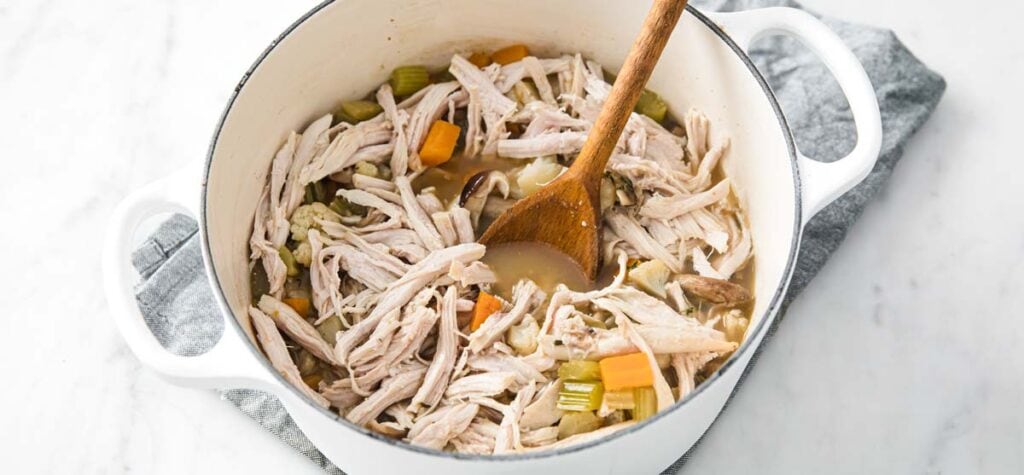 adding cooked turkey strips to a soup pot