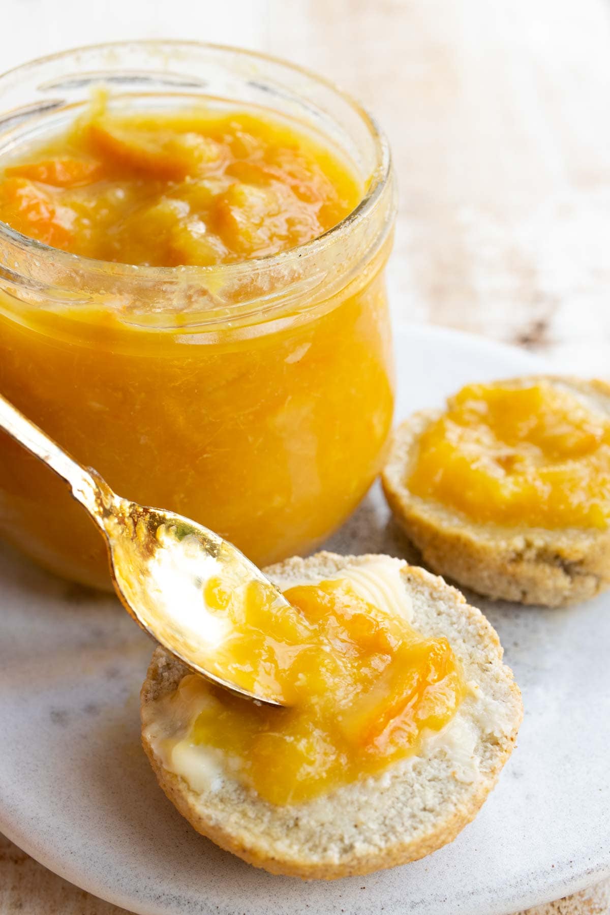 spreading orange marmalade onto a roll using a spoon