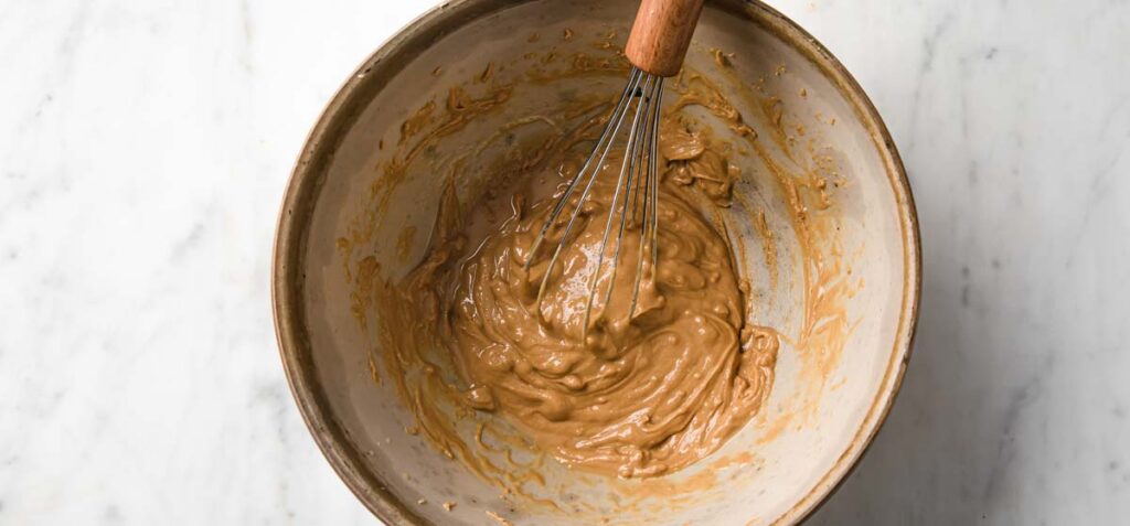 mixing peanut butter with a ballon whisk