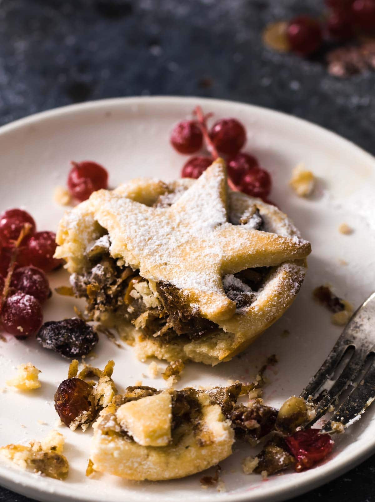 a mince pie on a plate with a bite taken out by a fork