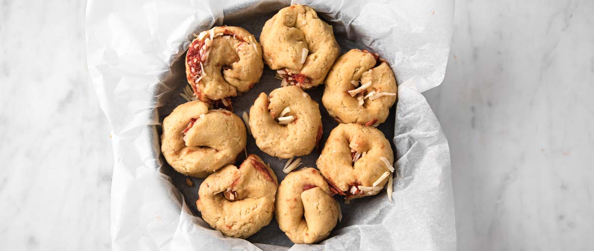 the unbaked pizza rolls in a round pan lined with parchment paper