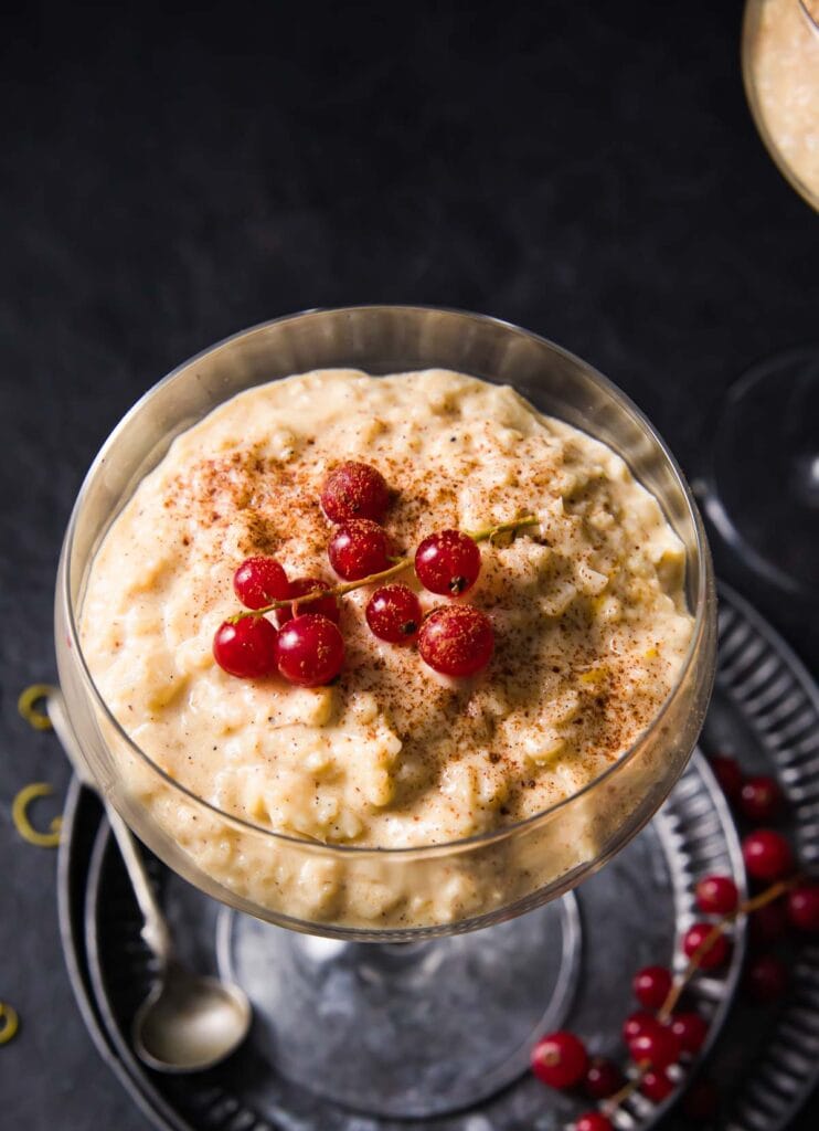 Healthy rice pudding in a glass serving bowl with nutmeg and red currants
