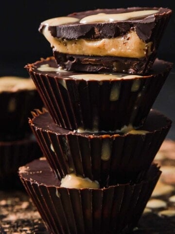 a stack of 4 keto peanut butter cups, the top one is halved showing the peanut centre
