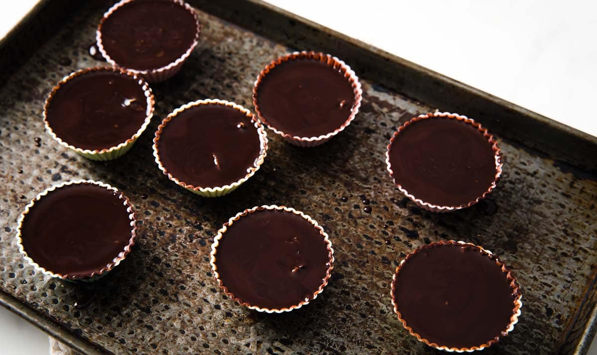 8 peanut butter cups on a baking tray, the chocolate is still liquid