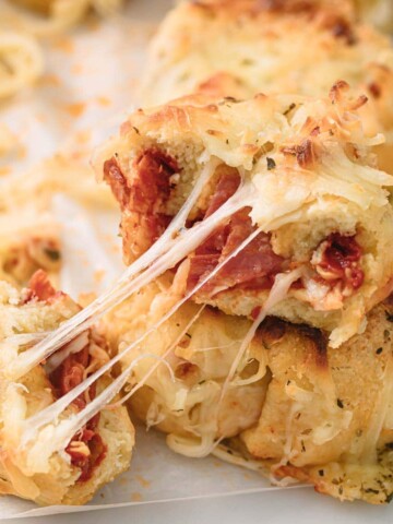 a halved keto pizza roll with melted cheese strings