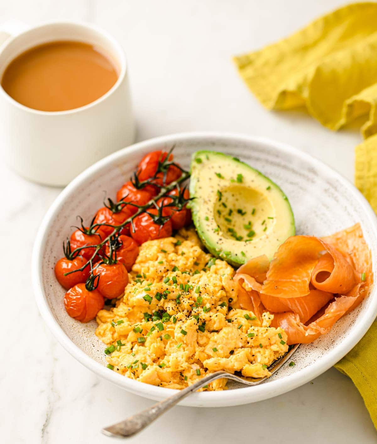 scrambled eggs with cherry tomatoes, avocado and salmon on a plate