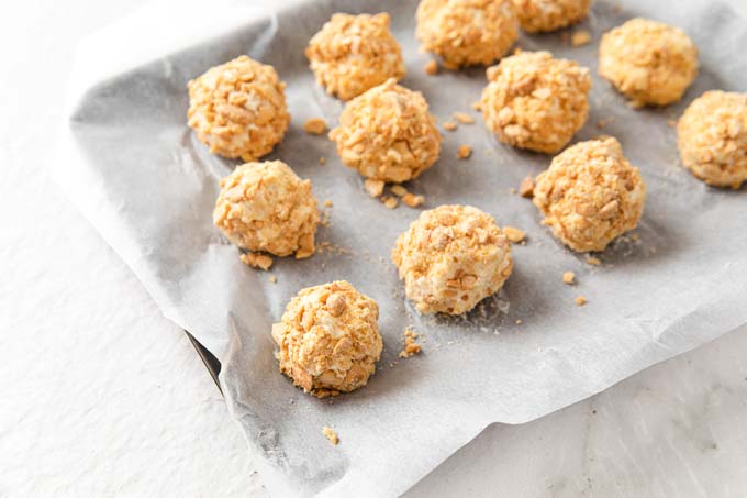 cheesecake bites rolled in roasted chopped almonds on parchment paper