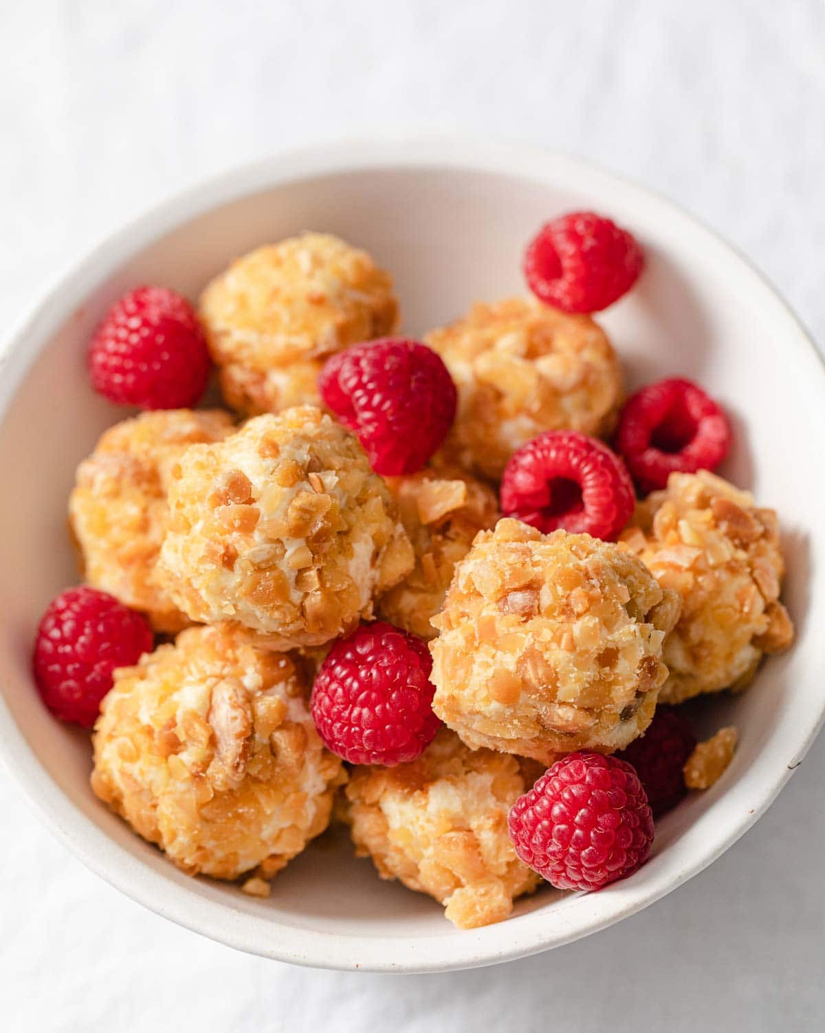 keto cheesecake bites in a bowl with raspberries