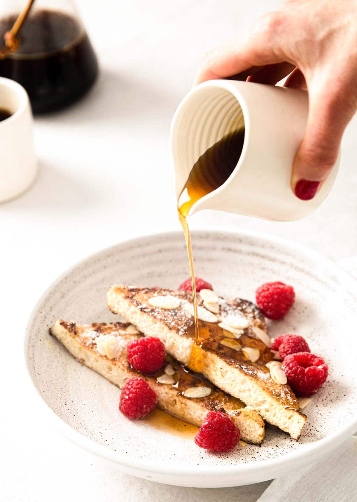 hand pouring sugar free syrup over french toast