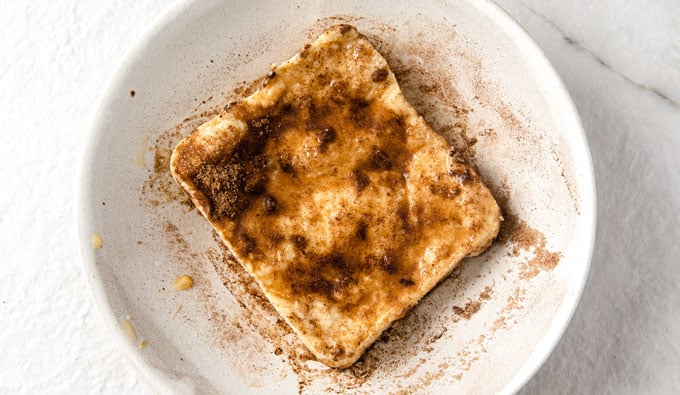 a slice of keto microwave bread on a plate with cinnamon and sweetener