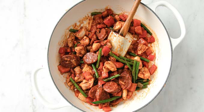 a saucepan with sliced chorizo, beans, chicken and peppers