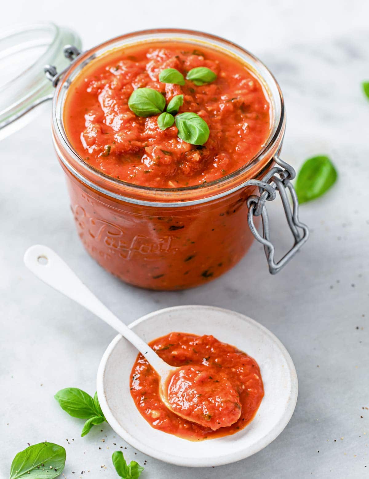 a glass jar with low carb pizza sauce and a small plate with sauce and a spoon