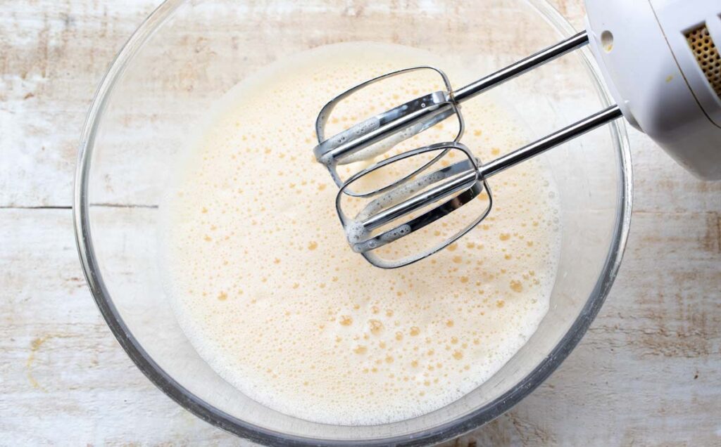 whisked frothy eggs in a bowl and an electric mixer