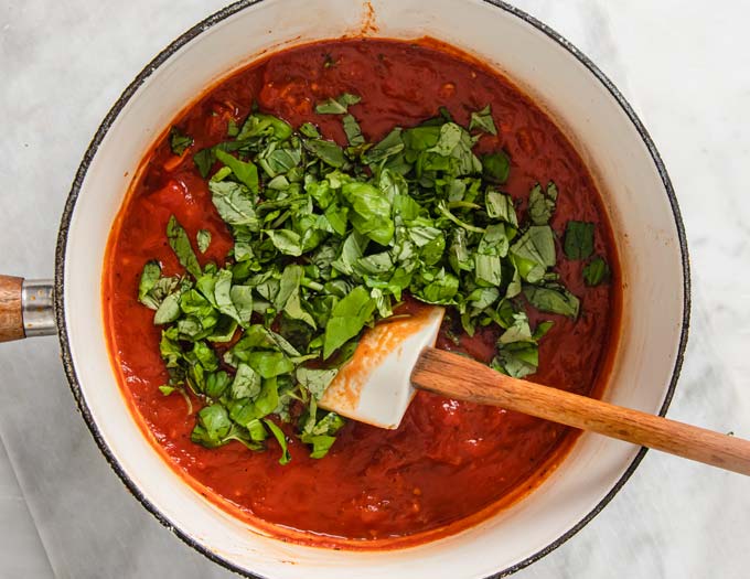 tomato sauce in a saucepan with fresh chopped basil