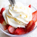 piping whipped cream onto strawberries