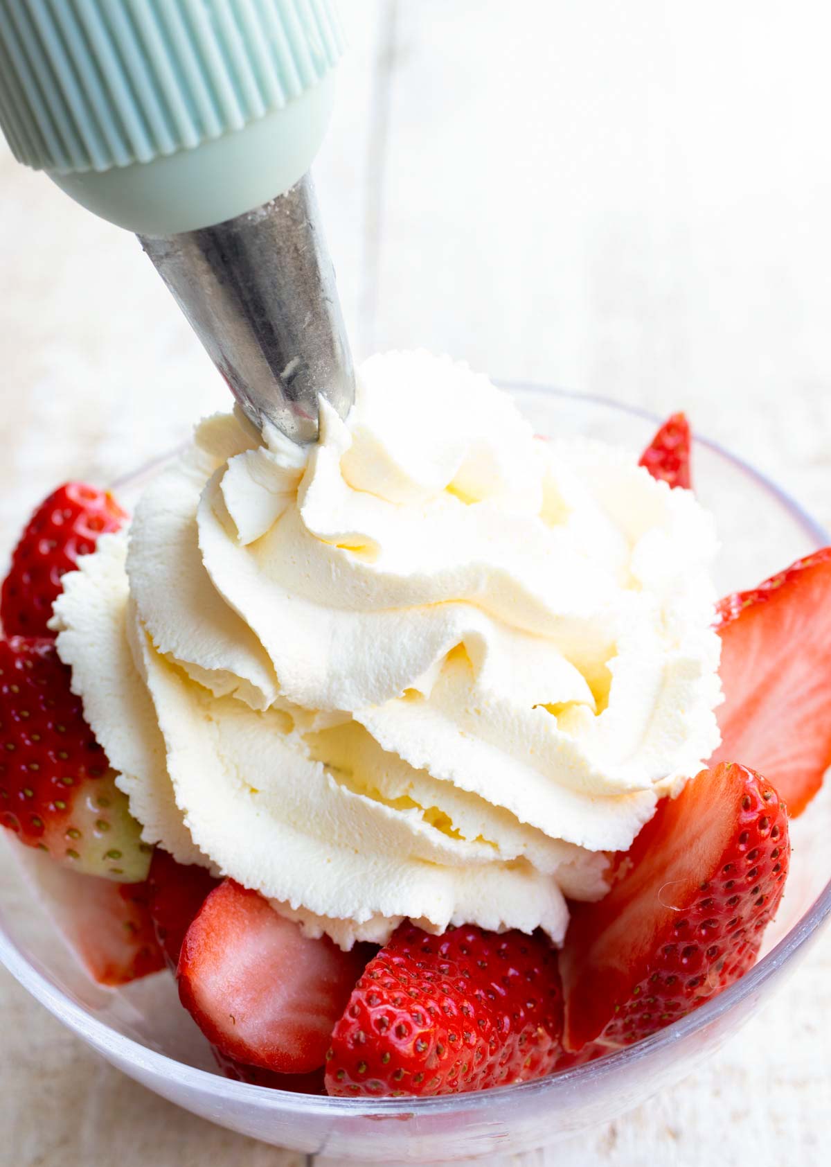 piping whipped cream onto strawberries