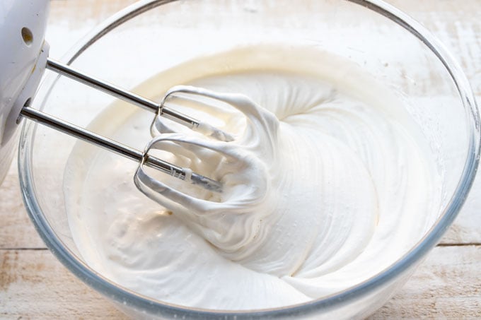 whipping cream in a glass bowl with an electric mixer