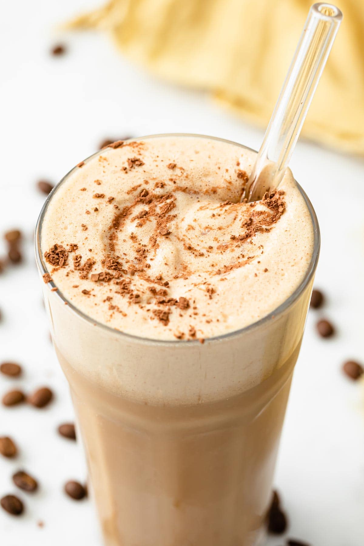 a glass with frothy keto coffee smoothie and a straw