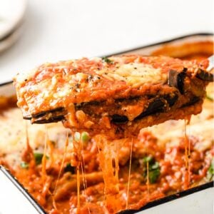 closeup of a spatula lifting a portion of keto eggplant parmesan from a casserole dish