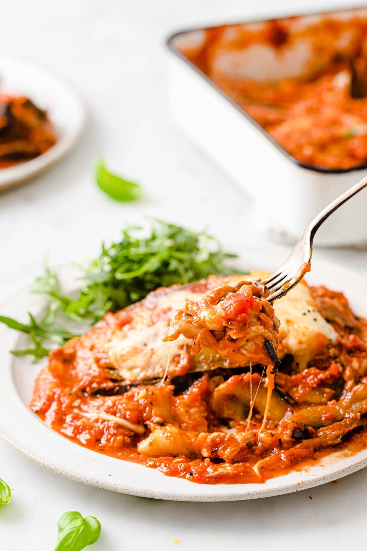 fork taking a bite of eggplant parmesan from a plate