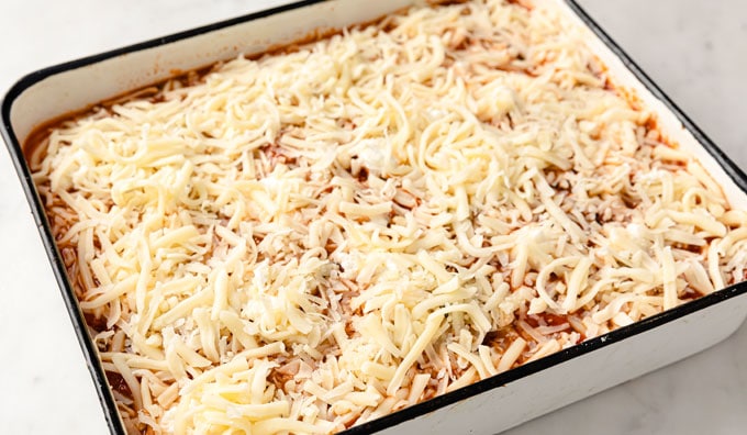 casserole dish with layered eggplant, tomato sauce and topped with grated mozzarella before baking