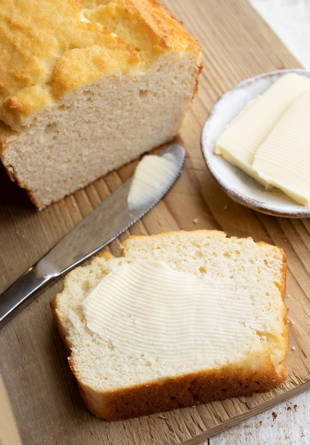 a slice of coconut flour bread spread with butter and a knife