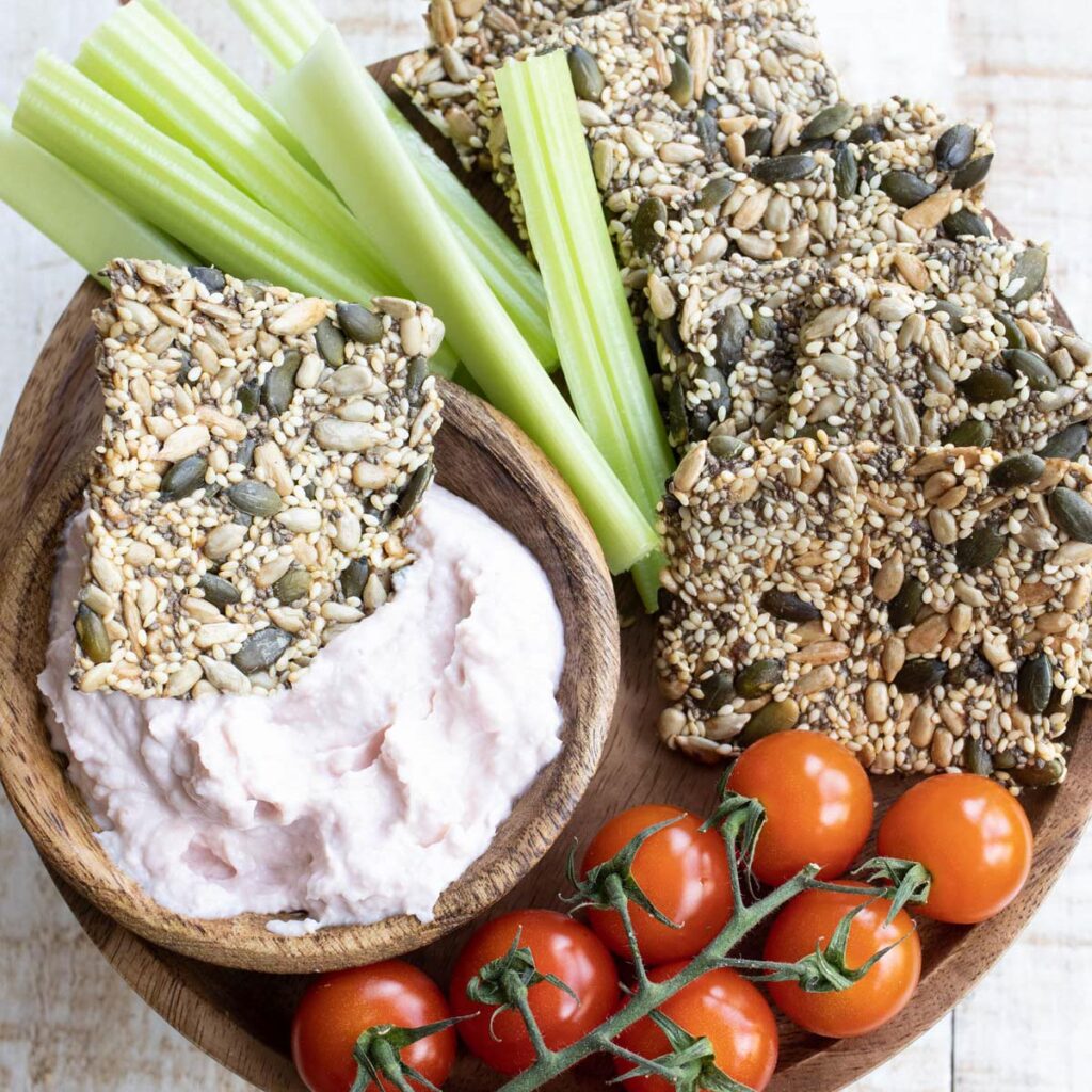 a snack platter with keto seed crackers, vegetables and dips