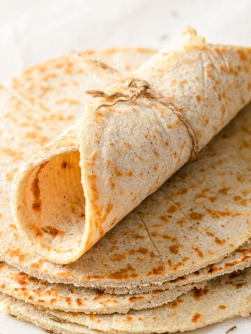 A rolled up coconut flour tortilla on a stack of tortillas