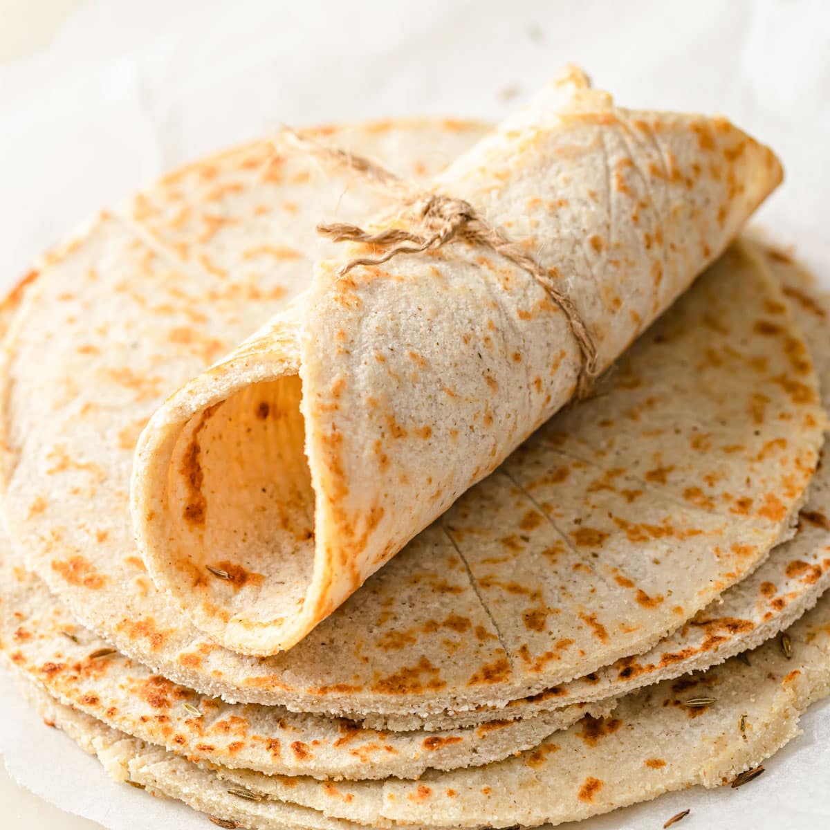 A rolled up tortilla on a stack of more tortillas.