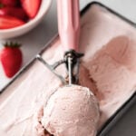a canister with strawberry ice cream and a scoop
