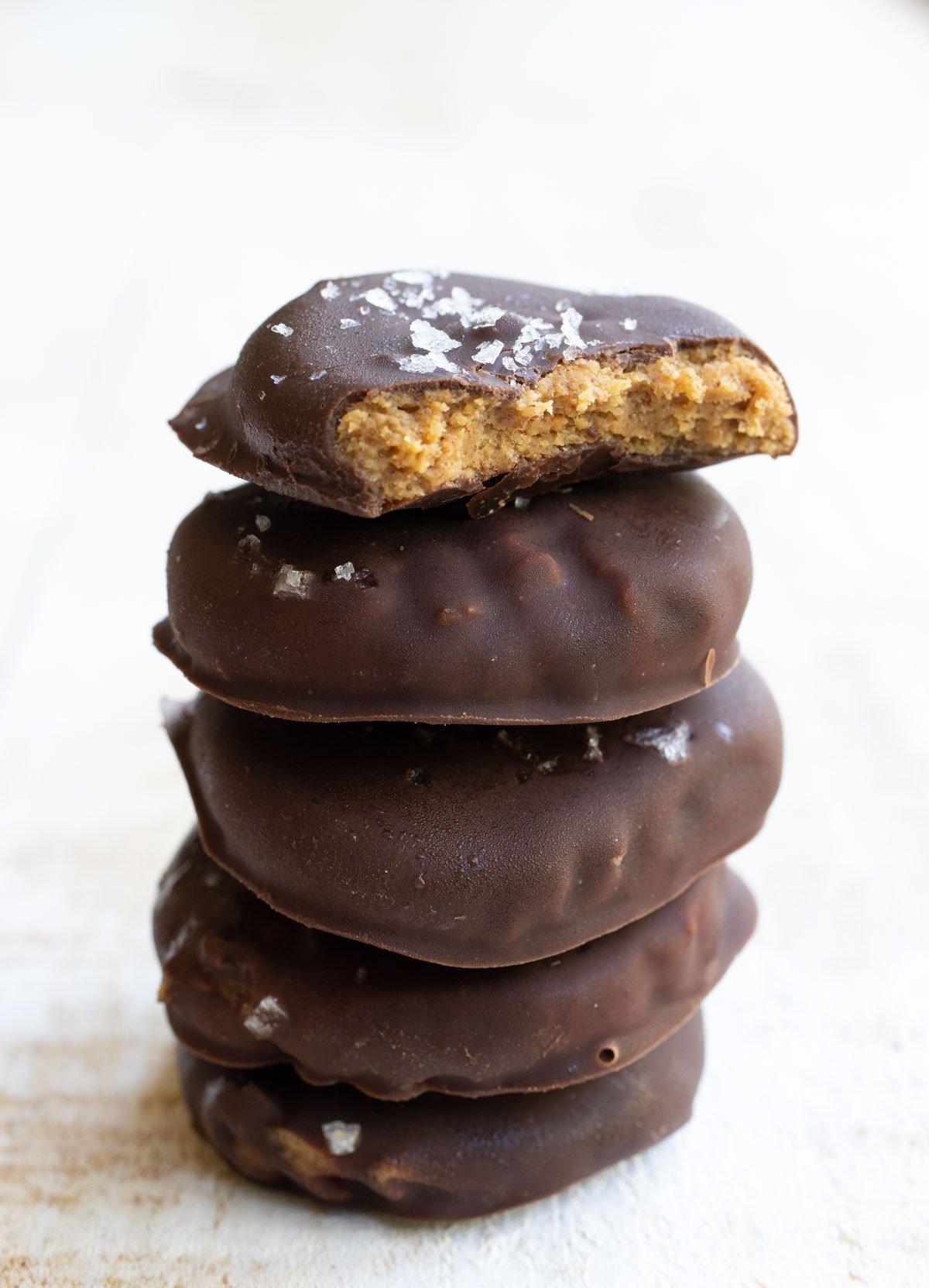 a bitten into cookie showing the peanut butter dough inside on a stack of more cookies