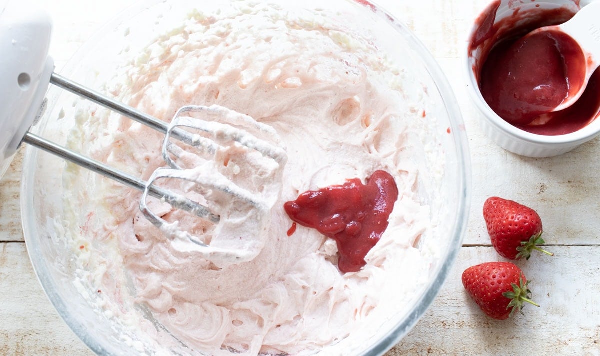 blending strawberry puree into the frosting with a mixer