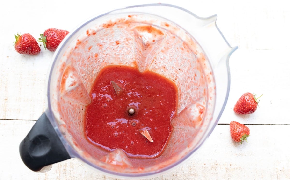 a blender jug with strawberry puree