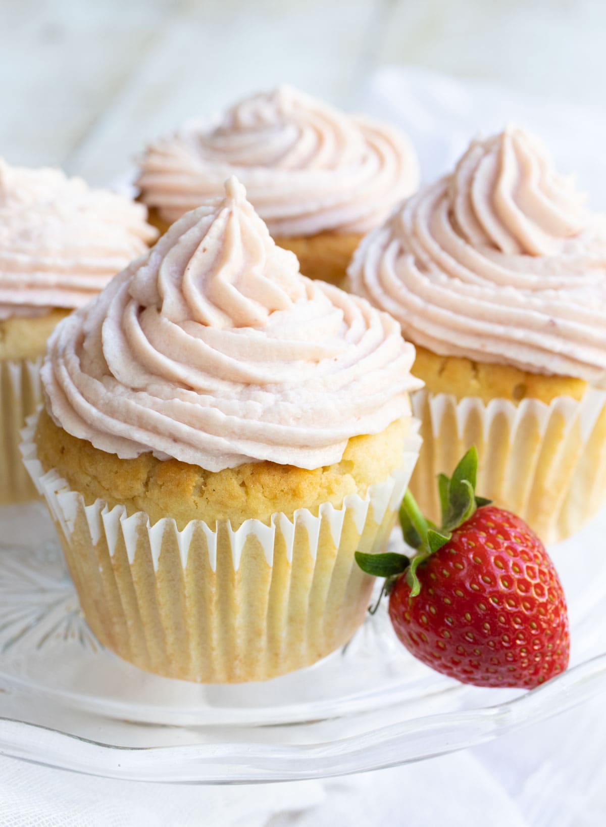 keto cupcakes with strawberry frosting and a strawberry on the side