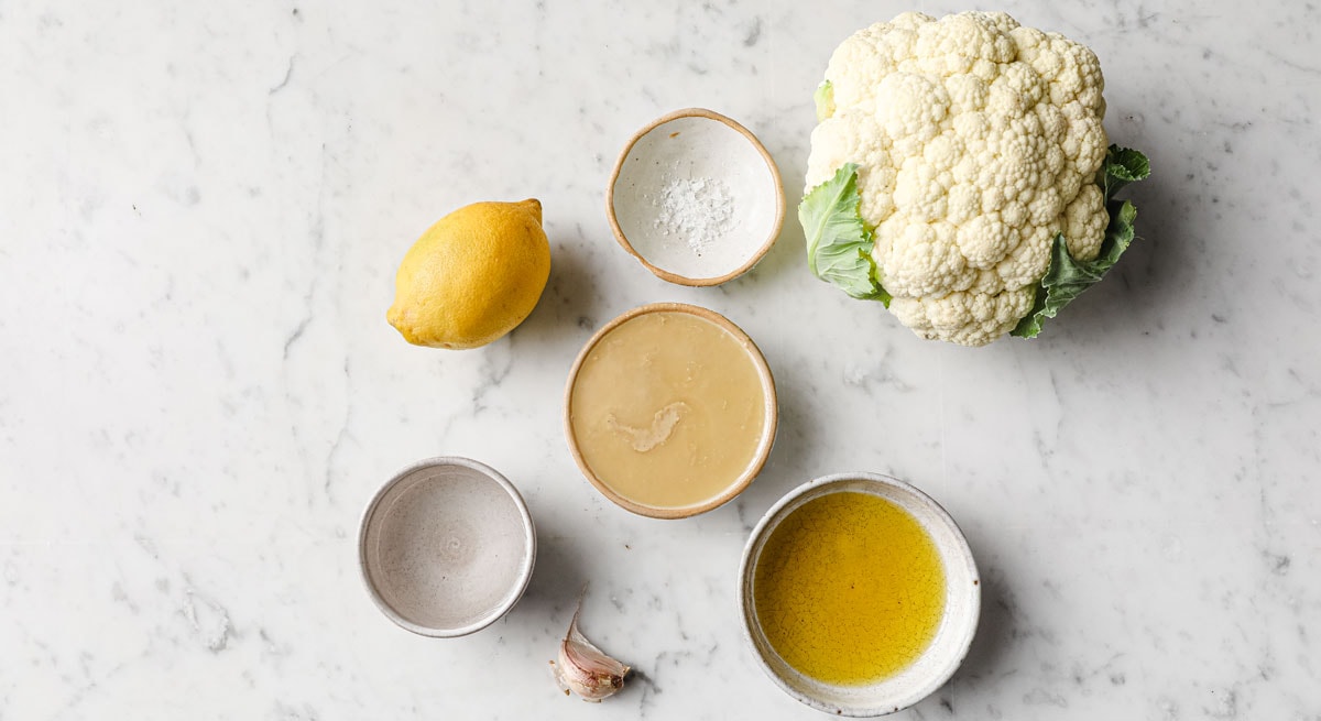 a cauliflower head and all other ingredients for this recipe measured into bowls