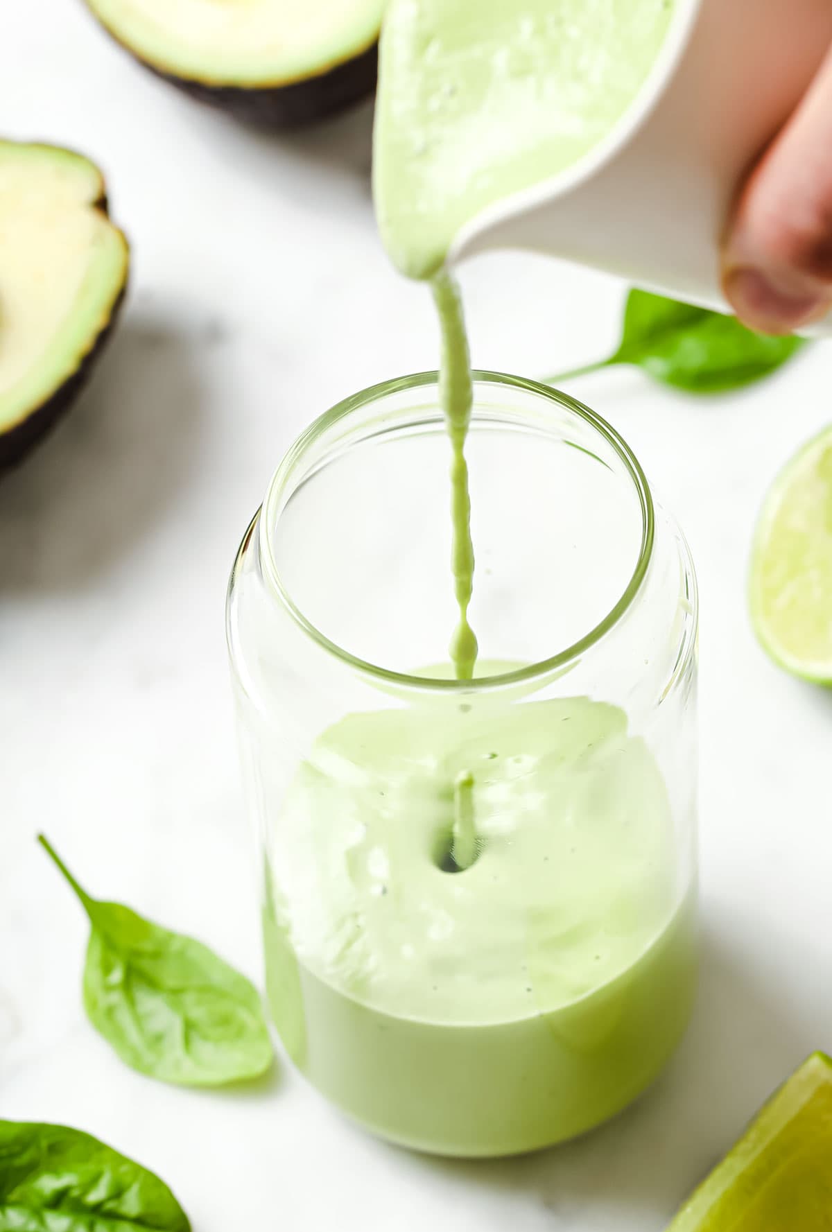 pouring avocado smoothie into a glass